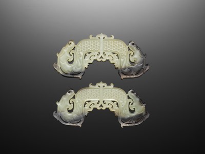 A RARE AND IMPORTANT PAIR OF WHITE AND BLACK JADE ‘DRAGON’ PENDANTS, HUANG, EARLY WESTERN HAN