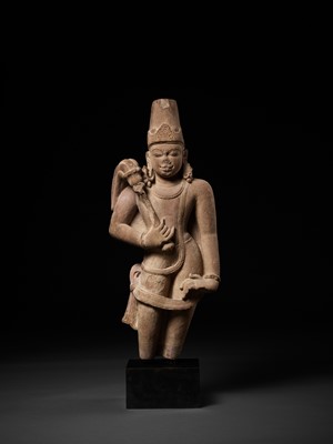 Lot 590 - A LARGE AND MASSIVE SANDSTONE FIGURE OF A CHAURI BEARER, 10TH CENTURY