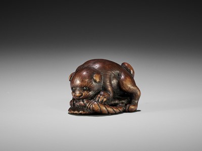Lot 145 - A WOOD NETSUKE OF A PUPPY PLAYING WITH A SANDAL, ATTRIBUTED TO KOKEI