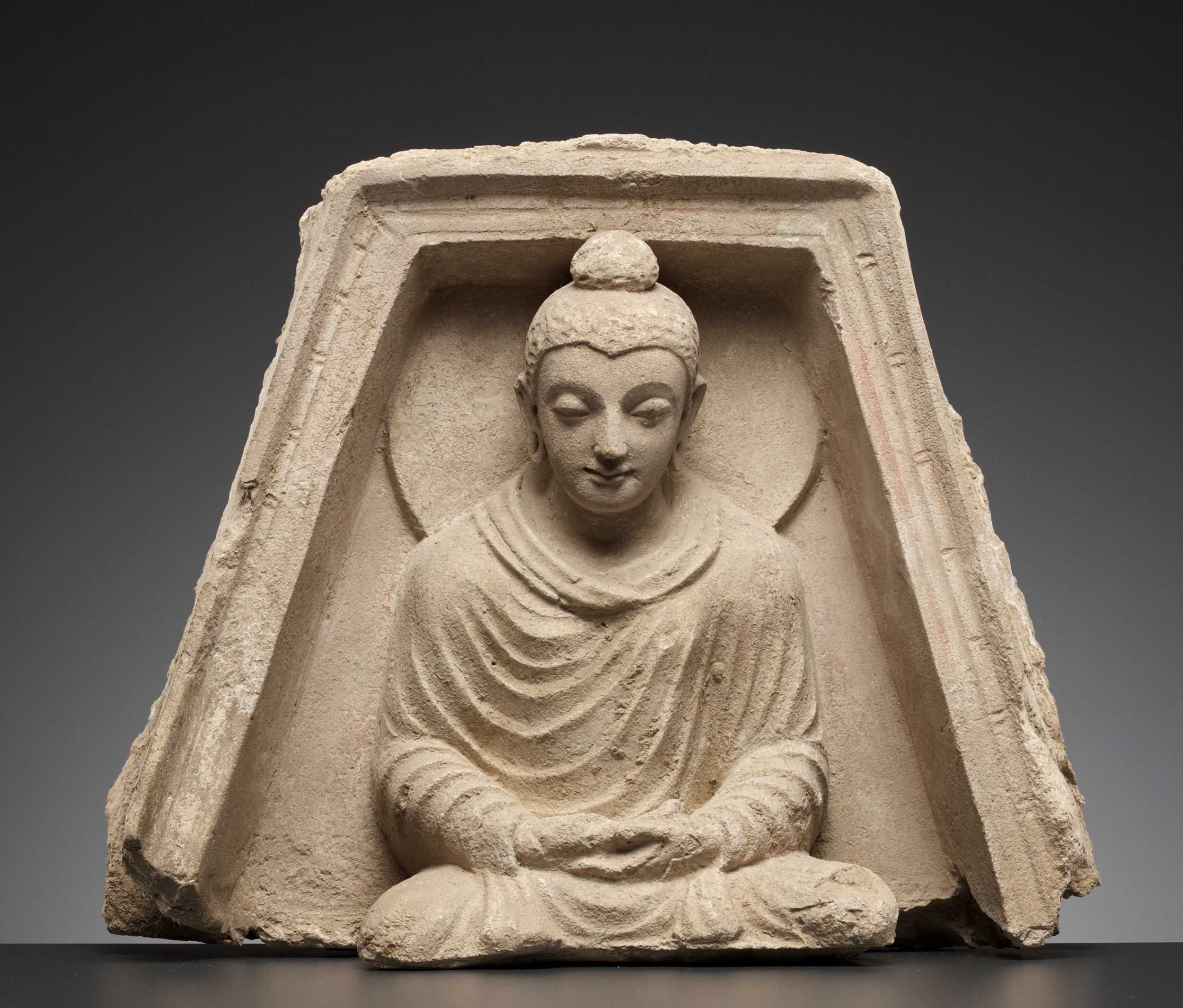 Lot 561 - A STUCCO RELIEF DEPICTING BUDDHA IN A TRAPEZOIDAL NICHE, KUSHAN PERIOD