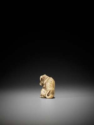 Lot 47 - AN IVORY NETSUKE OF A DOG AND YOUNG, ATTRIBUTED TO OKATOMO