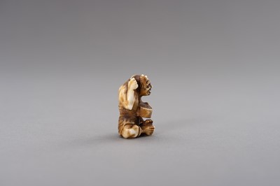 Lot 526 - AN IVORY NETSUKE OF AN ONI COMBING HIS HAIR