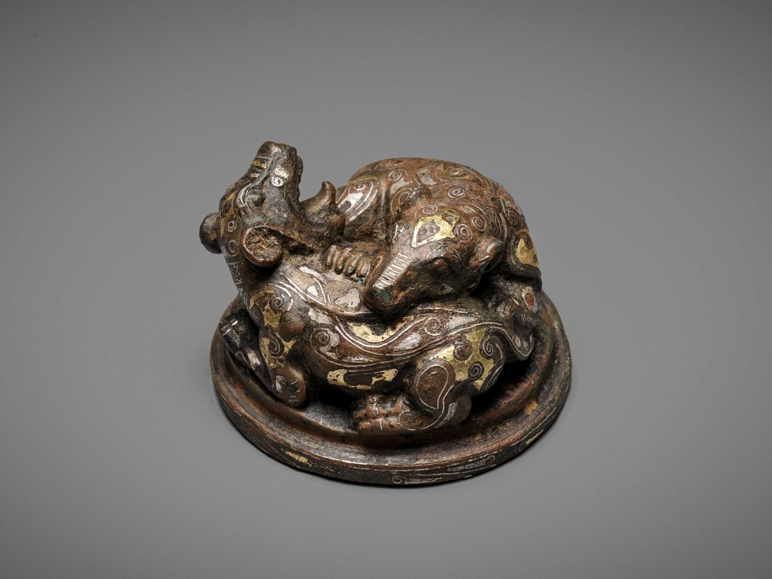 Lot 141 - A GOLD AND SILVER-INLAID ‘FIGHTING BEARS’ BRONZE MAT WEIGHT, WARRING STATES TO HAN DYNASTY