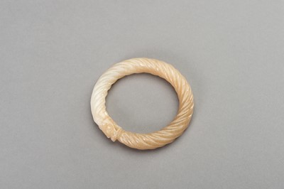 Lot 221 - A MOTTLED WHITE AND OCHRE ‘TWISTED ROPE’ JADE BANGLE, 1900s