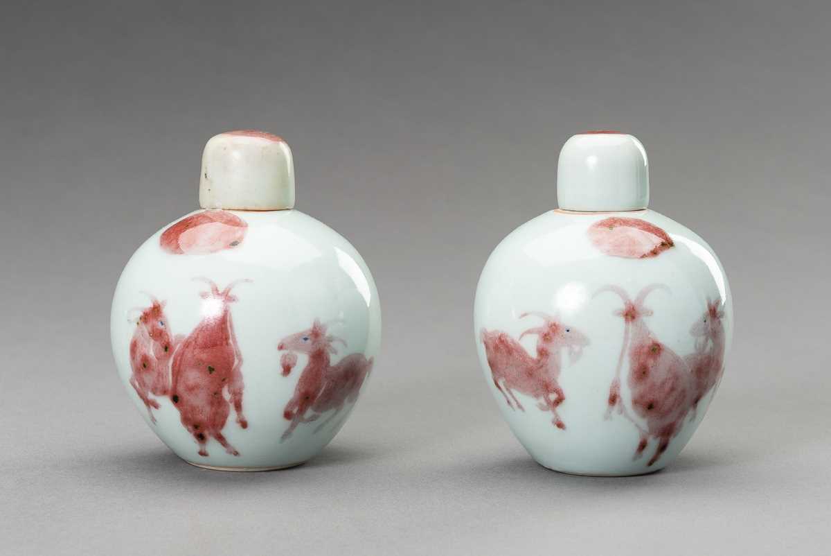 Lot 380 - A RARE PAIR OF COPPER-RED, LIDDED PORCELAIN JARLETS DEPICTING GOATS, 1900s