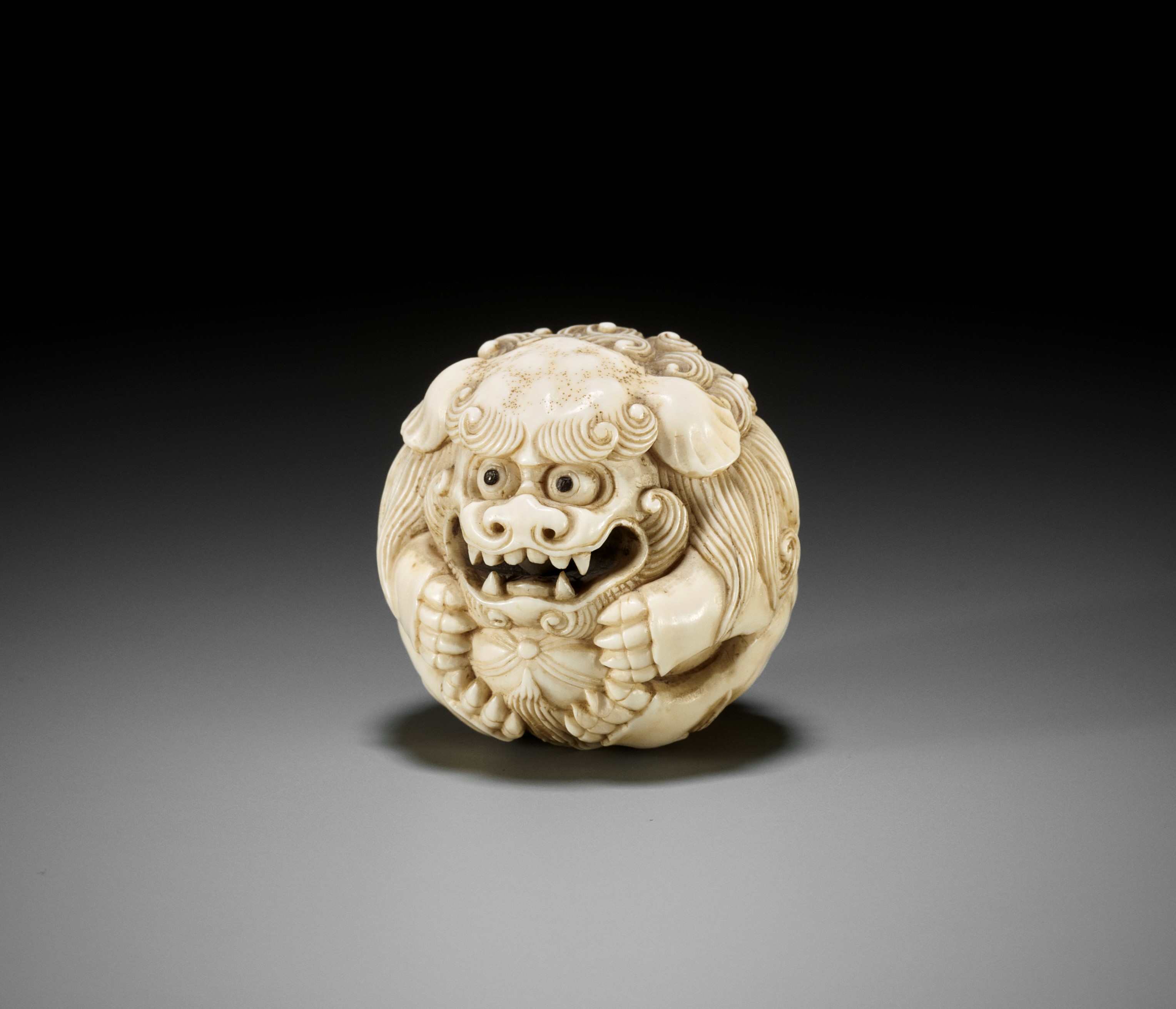 Lot 233 - AN IVORY NETSUKE OF A SHISHI BALL