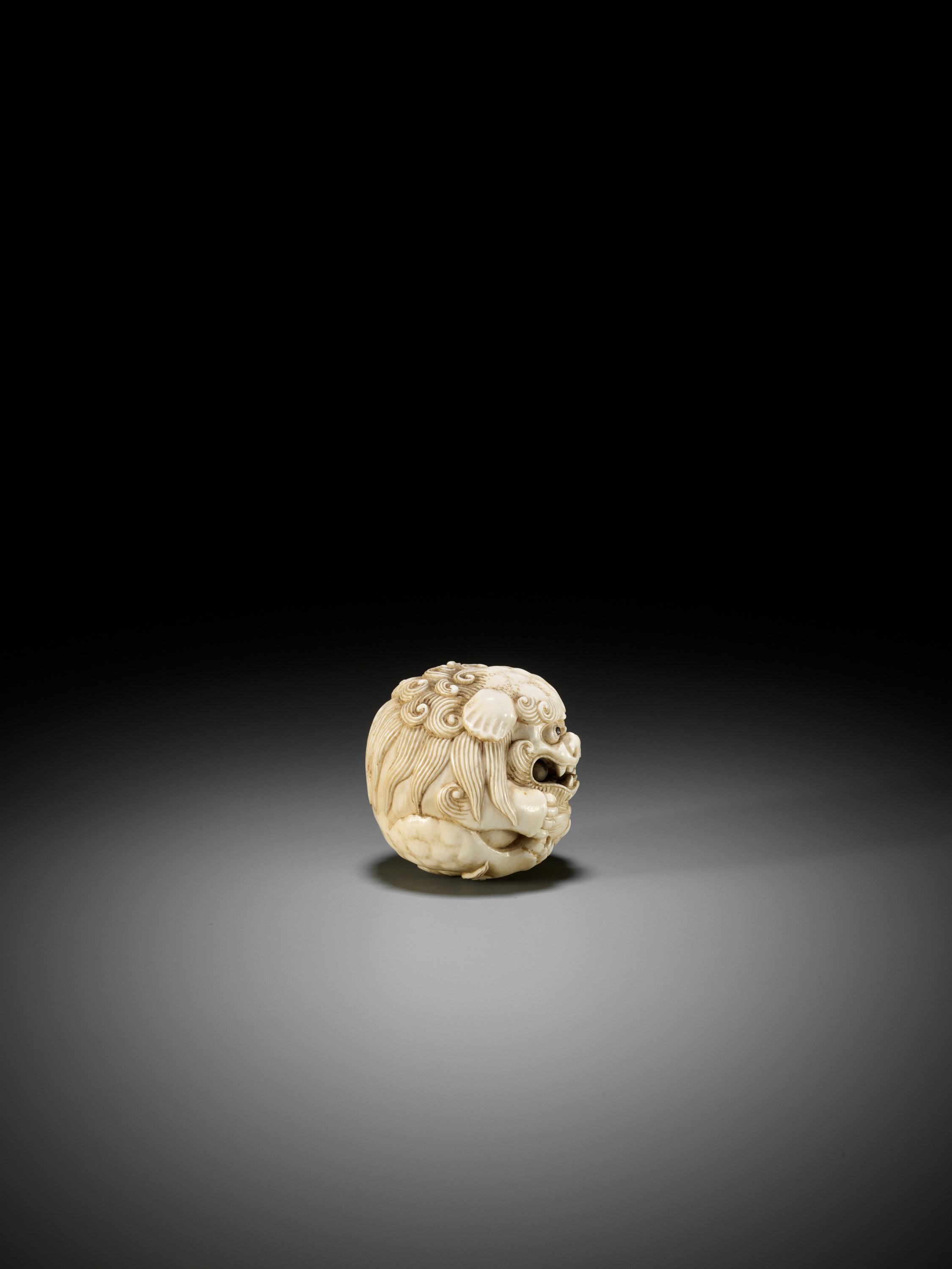 Lot 233 - AN IVORY NETSUKE OF A SHISHI BALL