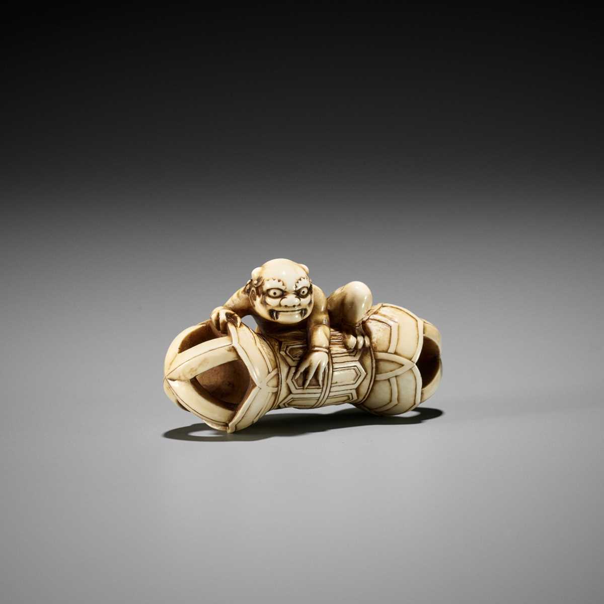 Lot 209 - A RARE IVORY NETSUKE OF AN ONI ON A KONGO (VAJRA)