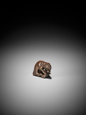 A FINE WOOD NETSUKE OF A WOLF WITH HAUNCH OF VENISON