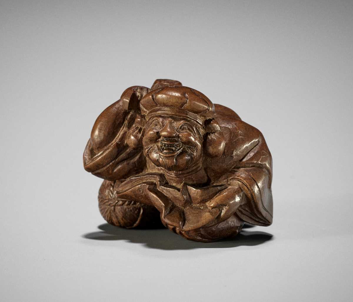 Lot 678 - MINZAN: AN UNUSUAL WOOD NETSUKE OF DAIKOKU