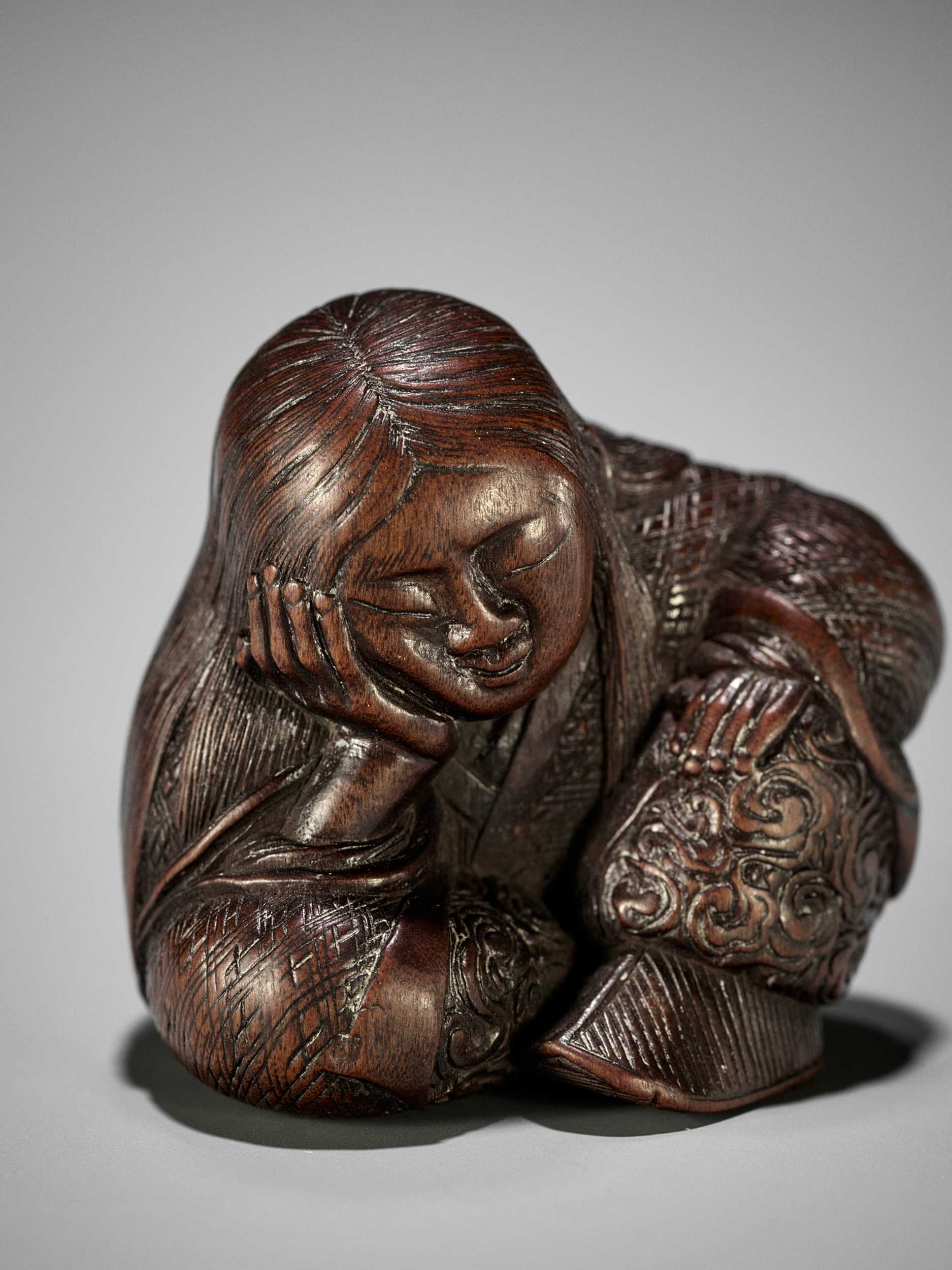 Lot 1449 - TADATOSHI: A SUPERB NAGOYA SCHOOL WOOD NETSUKE OF A SEATED SLEEPING SHOJO