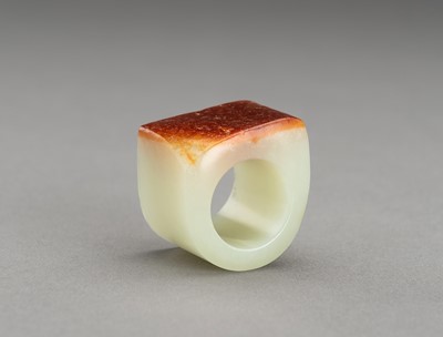 Lot 181 - A PALE CELADON AND RUSSET JADE ARCHER’S RING
