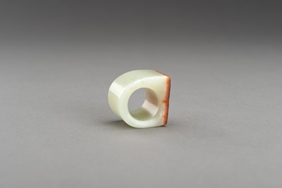 Lot 181 - A PALE CELADON AND RUSSET JADE ARCHER’S RING