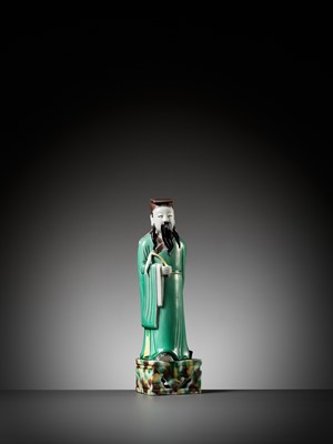 Lot 397 - A GREEN, YELLOW AND AUBERGINE-GLAZED BISCUIT FIGURE OF A DAOIST IMMORTAL, KANGXI PERIOD