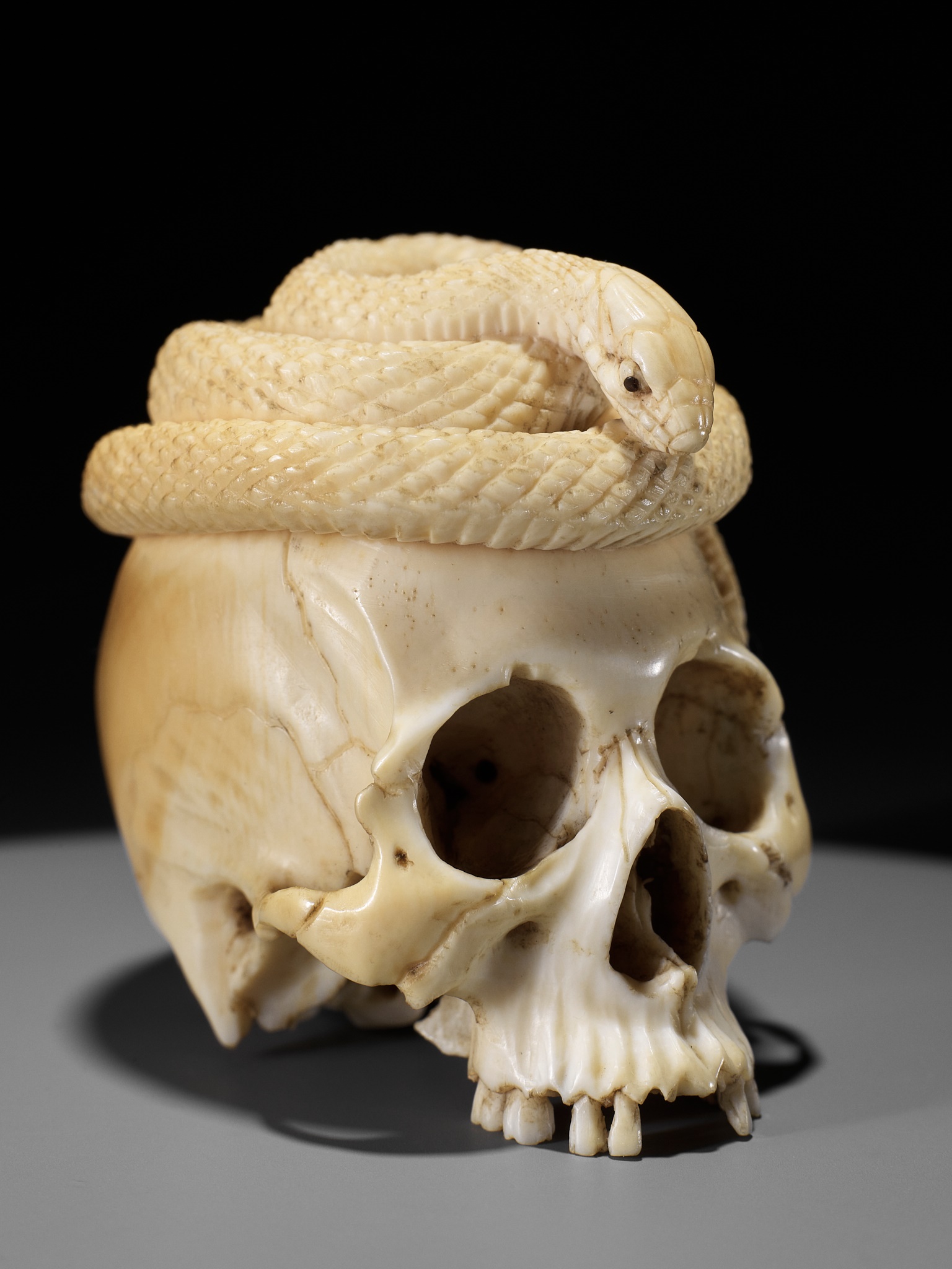 Lot 272 - A SUPERB IVORY OKIMONO OF A SKULL WITH SNAKE