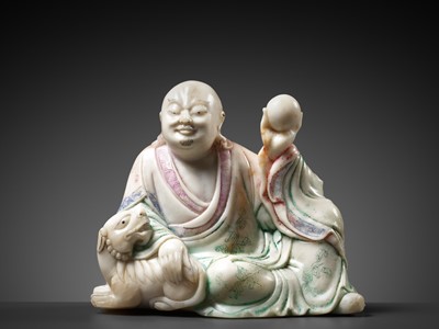 Lot 298 - A BAIFURONG SOAPSTONE FIGURE OF XIAOSHI LUOHAN WITH A BUDDHIST LION, 17TH-18TH CENTURY