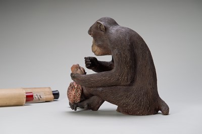 Lot 256 - A RARE AND LARGE PAINTED POTTERY OKIMONO OF A MONKEY EXAMINING A MONKEY NETSUKE