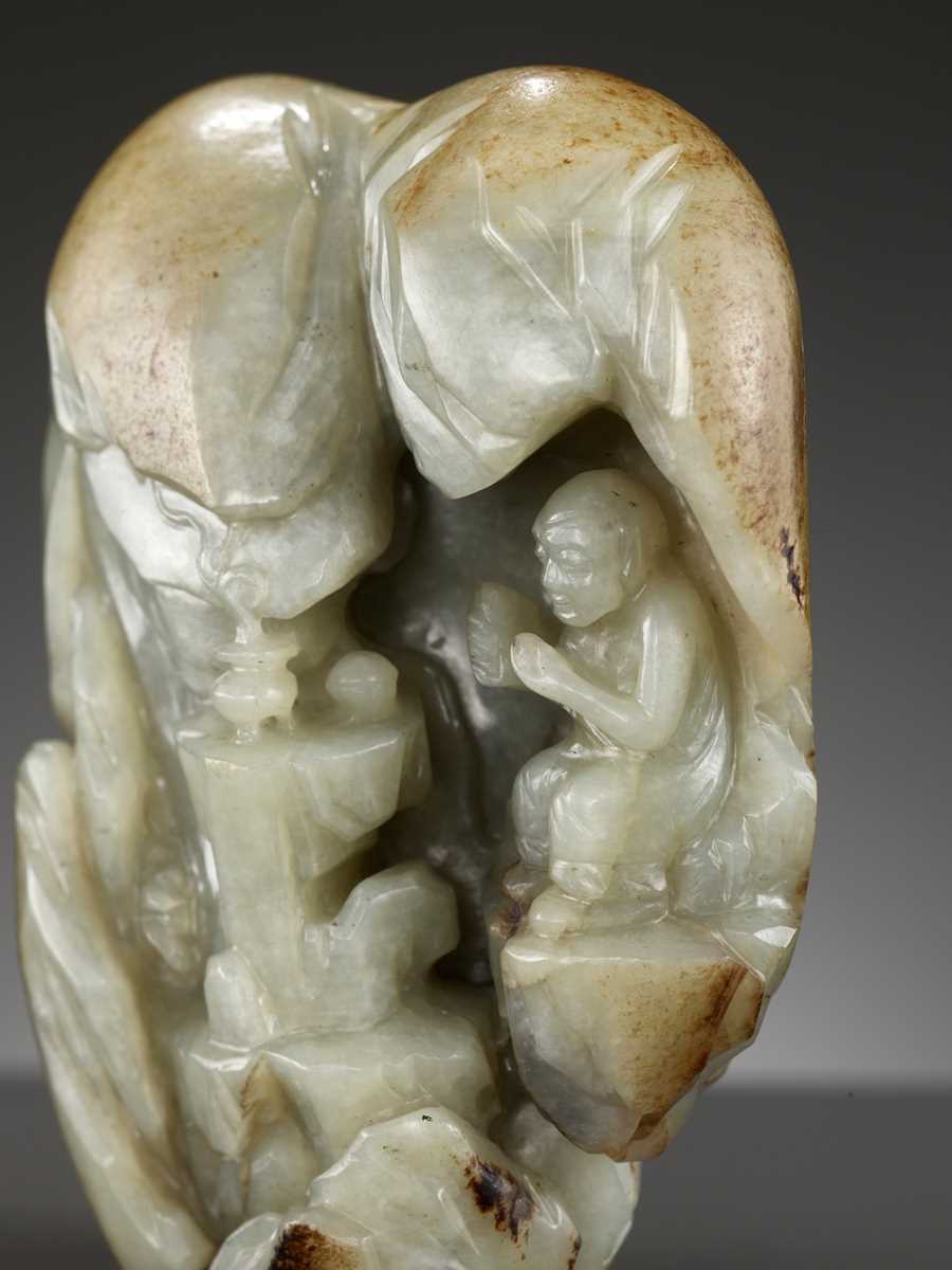 Lot 39 - A CELADON AND RUSSET JADE ‘LUOHAN IN A GROTTO’ BOULDER, 17TH - 18TH CENTURY