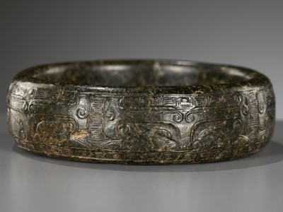 Lot 327 - AN ARCHAISTIC SPINACH-GREEN JADE ‘TAOTIE’ BANGLE, LATE MING DYNASTY