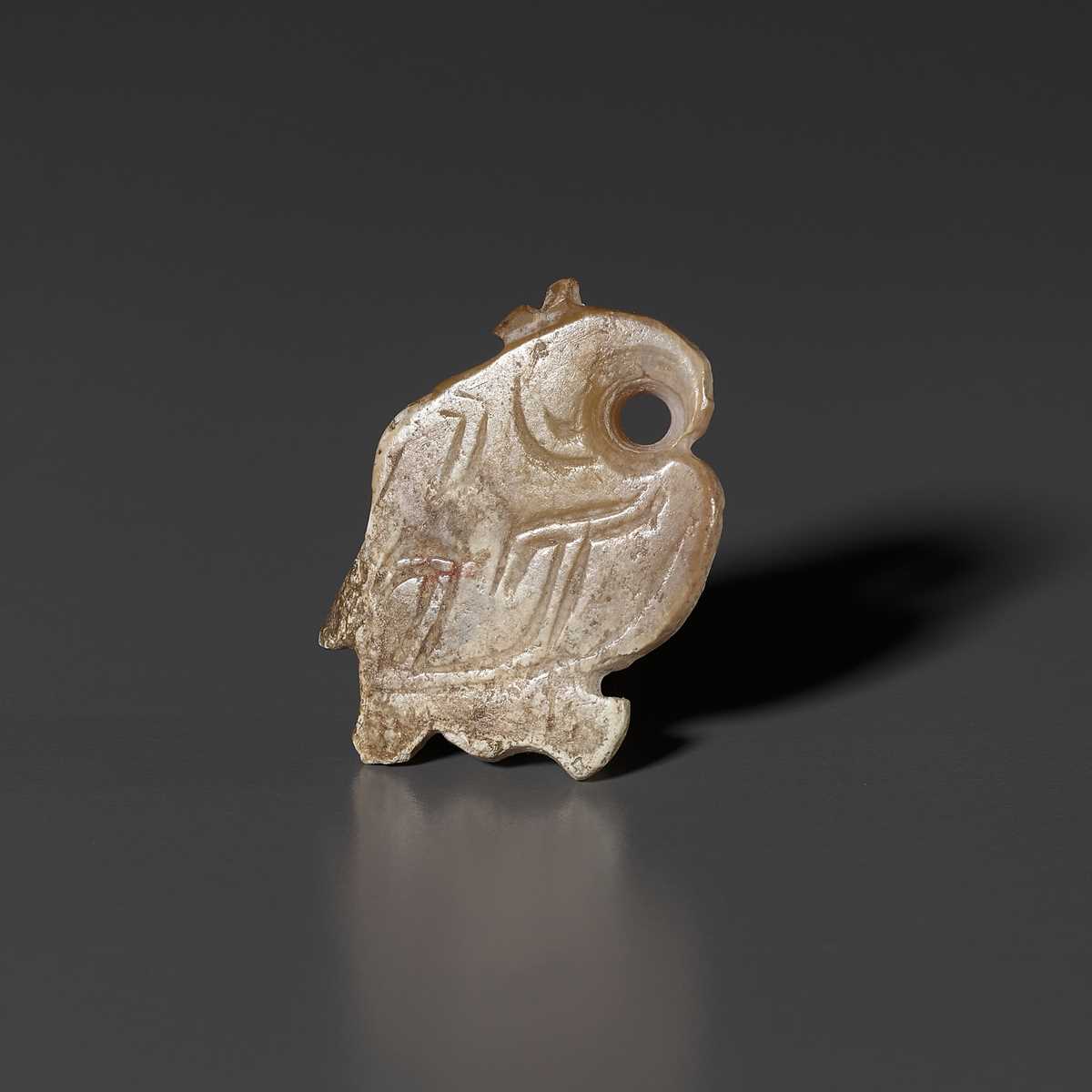 Lot 1025 - A PALE CELADON AND RUSSET JADE ‘BIRD’ PENDANT, LATE SHANG DYNASTY