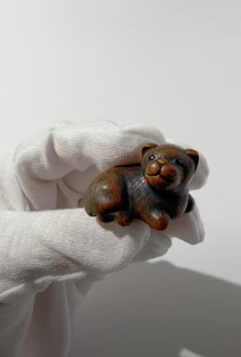 Lot 372 - A TANBA SCHOOL WOOD NETSUKE OF A RECLINING PUPPY