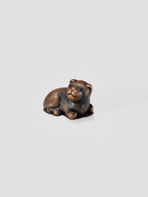 Lot 372 - A TANBA SCHOOL WOOD NETSUKE OF A RECLINING PUPPY