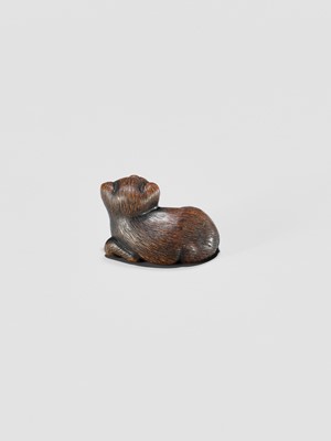 Lot 372 - A TANBA SCHOOL WOOD NETSUKE OF A RECLINING PUPPY