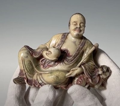 A BAIFURONG SOAPSTONE FIGURE OF XIAOSHI LUOHAN WITH A BUDDHIST LION, EARLY QING DYNASTY