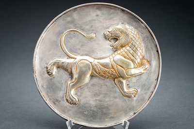 Lot 780 - A PERSIAN PARCEL-GILT SILVER REPOUSSÉ ‘LION’ DISH