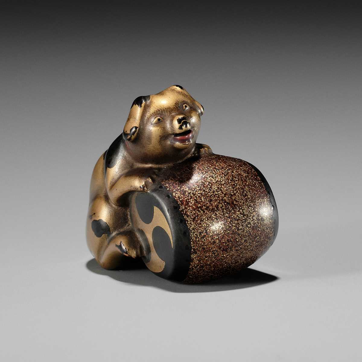 Lot 405 - A CHARMING GOLD LACQUER NETSUKE OF A DOG WITH DRUM