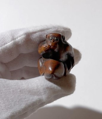 Lot 344 - A WOOD NETSUKE OF A MONKEY EATING A PEACH, ATTRIBUTED TO MIWA