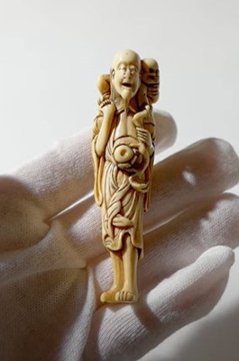 Lot 322 - A RARE IVORY NETSUKE OF A SENNIN WITH ONI