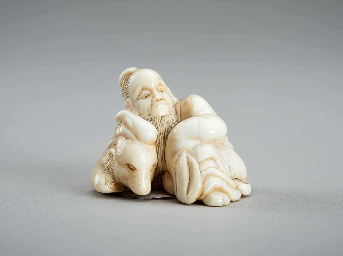 Lot 876 - AN IVORY NETSUKE OF A SAGE RECLINING ON A GOAT, EDO PERIOD