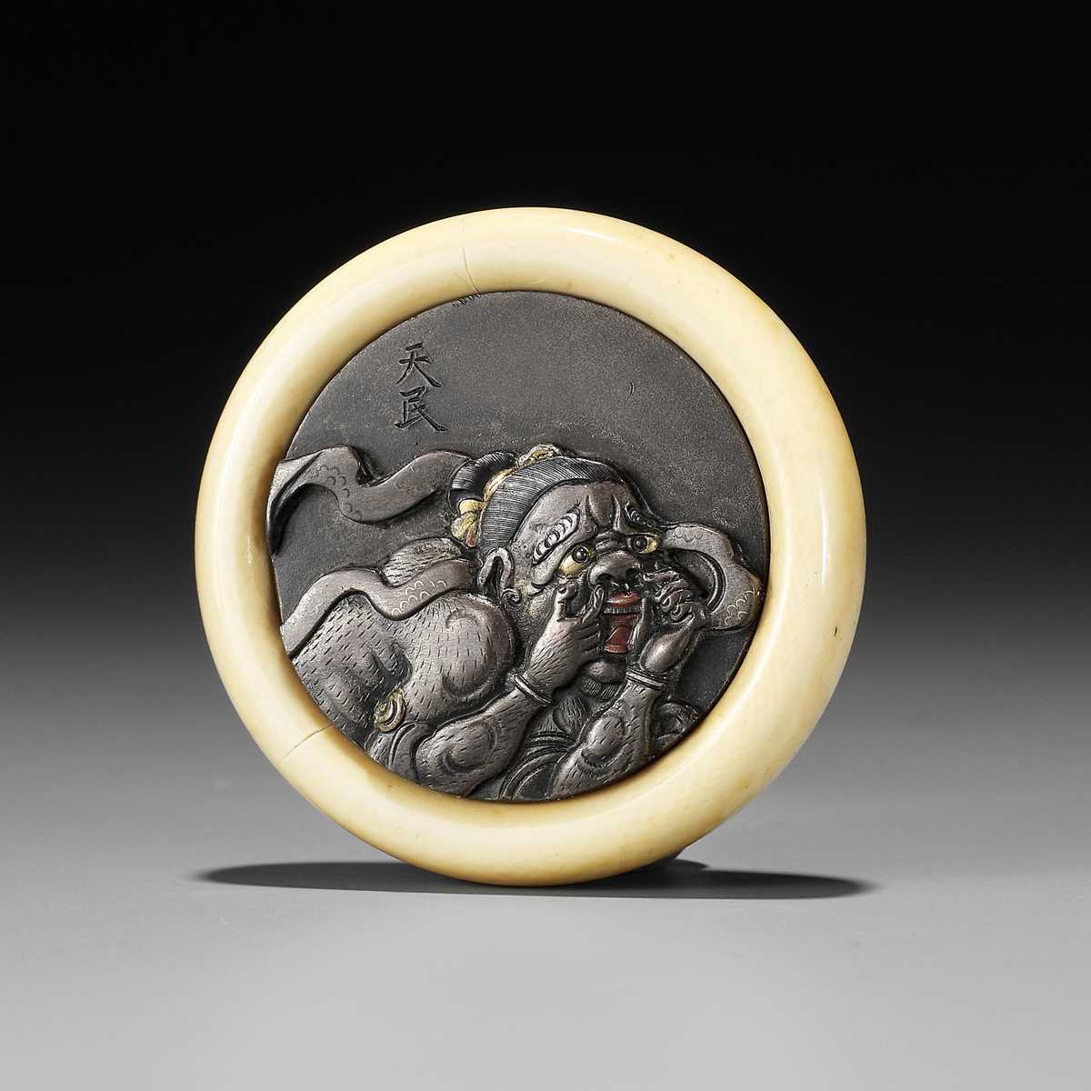 Lot 398 - TENMIN: A KAGAMIBUTA NETSUKE DEPICTING A NIO PULLING A GRIMACE