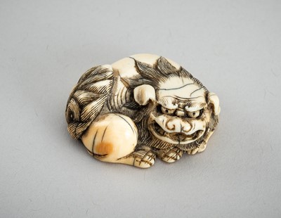 Lot 713 - AN IVORY NETSUKE OF A RECLINING SHISHI, EDO PERIOD