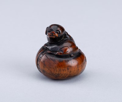 Lot 725 - SHOICHI: A WOOD NETSUKE OF A PUPPY ON A BASE, EDO PERIOD