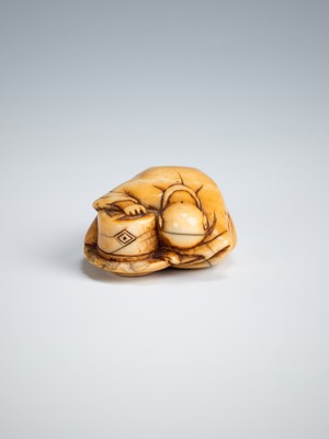 Lot 392 - AN OLD IVORY NETSUKE OF A TEA GRINDER NAPPING BESIDE A MILLSTONE