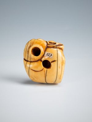 Lot 392 - AN OLD IVORY NETSUKE OF A TEA GRINDER NAPPING BESIDE A MILLSTONE