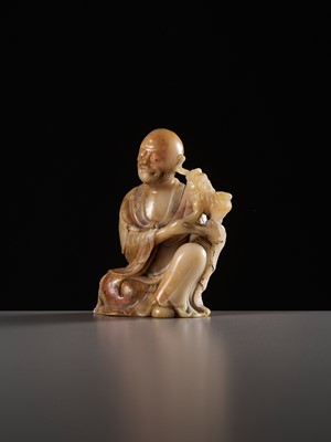 Lot 31 - A RARE SOAPSTONE FIGURE OF VIJRAPUTRA, AKA THE LAUGHING LION LUOHAN OR XIAOSHI LUOHAN, QING DYNASTY
