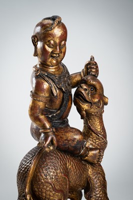 Lot 89 - A VERY LARGE GILT-LACQUERED WOOD STATUE OF YOUNG BUDDHA RIDING QILIN
