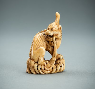 Lot 710 - AN IVORY NETSUKE OF A MYTHICAL BEAST, EDO PERIOD