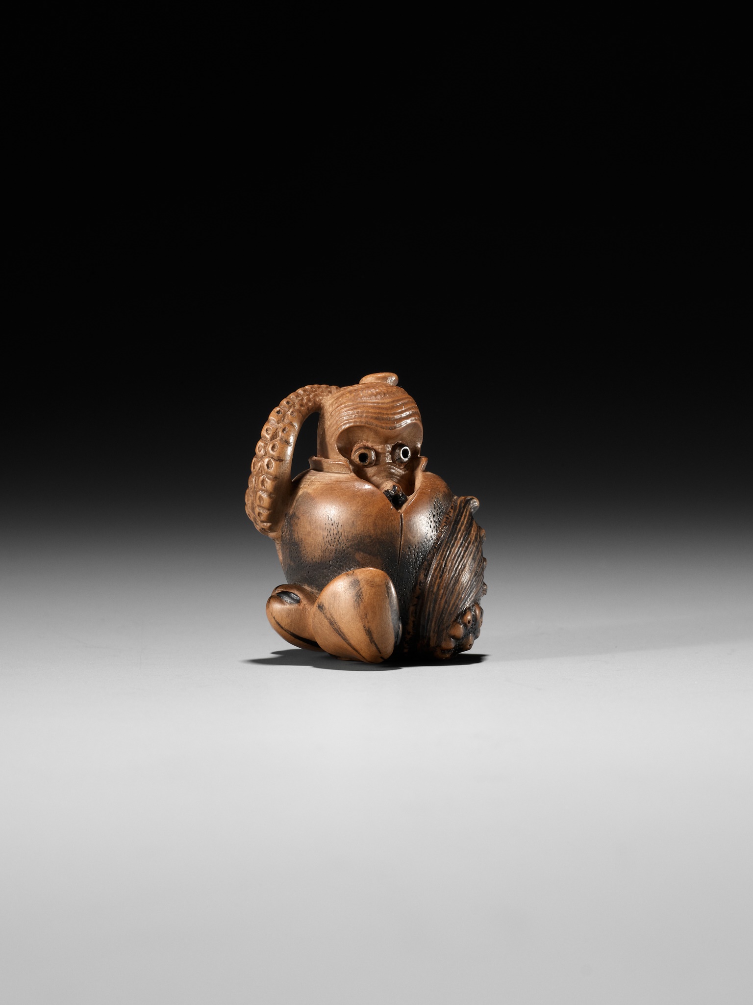 Lot 377 - TOMONOBU: A STAINED WOOD NETSUKE OF A