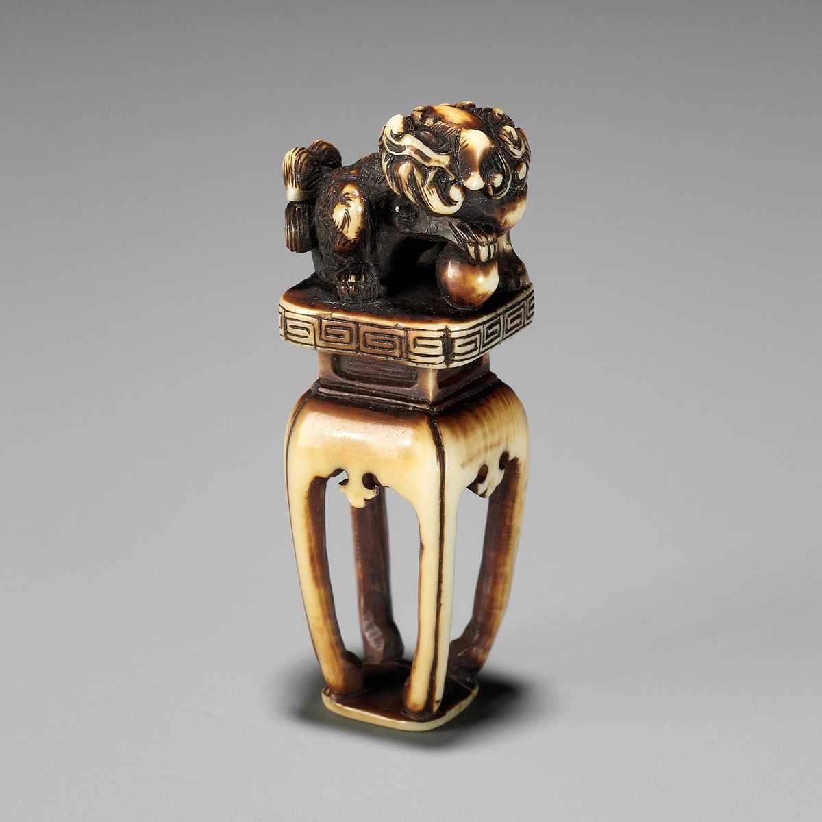 Lot 151 - AN IVORY SEAL-TYPE (INGYO) NETSUKE OF A SHISHI, ATTRIBUTED TO ANRAKU