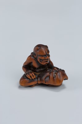 Lot 389 - GYOKKEI: A WOOD NETSUKE OF AN ONI INSPECTING A SHOKI MASK