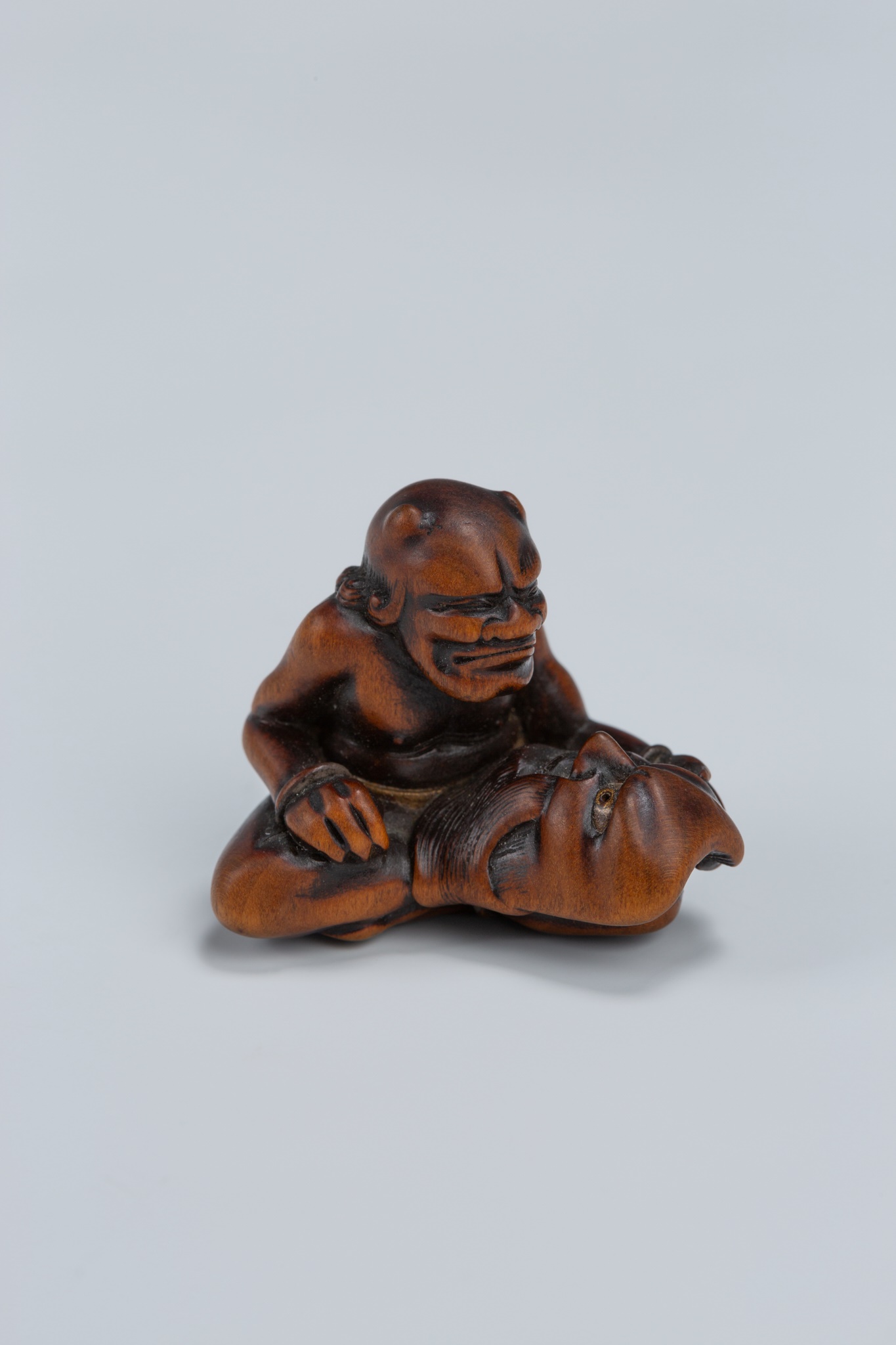 Lot 389 - GYOKKEI: A WOOD NETSUKE OF AN ONI INSPECTING