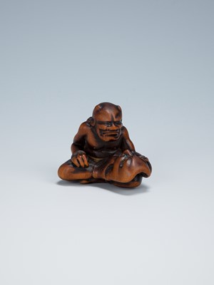 Lot 389 - GYOKKEI: A WOOD NETSUKE OF AN ONI INSPECTING A SHOKI MASK