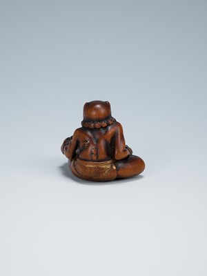 Lot 389 - GYOKKEI: A WOOD NETSUKE OF AN ONI INSPECTING A SHOKI MASK