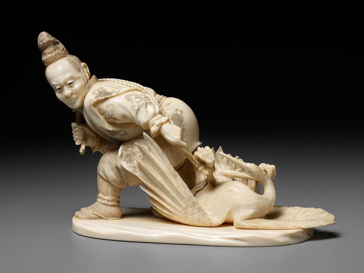 Lot 141 - KOGETSU: A FINE IVORY OKIMONO OF A HUNTER SNARING A CRANE