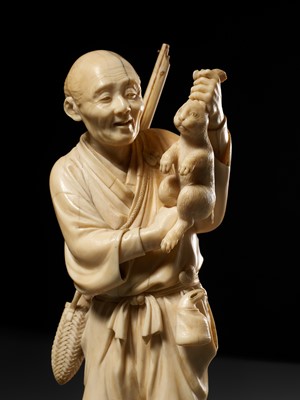 Lot 138 - KOSEI: A FINE TOKYO SCHOOL IVORY OKIMONO OF A HUNTER HOLDING A HARE