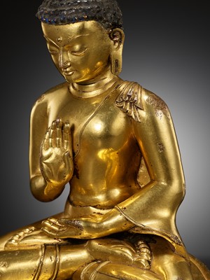 Lot 179 - A GILT COPPER ALLOY FIGURE OF AMOGHASIDDHI, ONE OF THE FIVE WISDOM BUDDHAS, POSSIBLY DENSATIL, TIBET, 14TH-15TH CENTURY